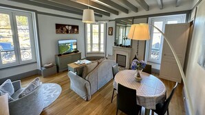 A living room with a sofa, a dining table with chairs, a TV, and a fireplace. - Quiet corner near the mountain road (Mont-Dore)