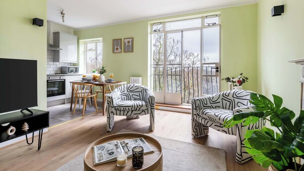A modern living room with a dining area, a kitchen, and a balcony with large windows. - Cozy 1BR Near Hyde Park & Notting Hill (London)