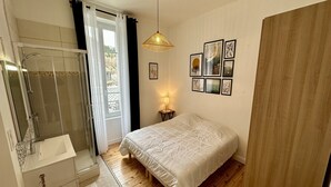 Ein Schlafzimmer mit einem großen Bett, einer Dusche, einem Waschbecken und einem kleinen Tisch mit einer Lampe.