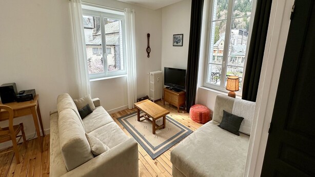 Ein Wohnzimmer mit einer Couch, einem Couchtisch, einem Fernseher und einer Lampe.