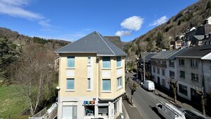 A multi-story building with a sloped roof, located in a hilly area with a clear sky. - Quiet corner near the mountain road (Mont-Dore)