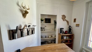 A kitchen with a wooden table, knife block, shelves with dishes, and a clock. - Quiet corner near the mountain road (Mont-Dore)