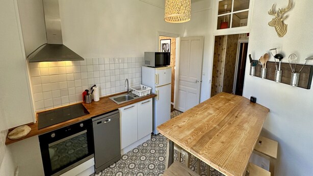 A compact kitchen with a wooden countertop, stainless steel appliances, and a hanging light fixture. - Quiet corner near the mountain road (Mont-Dore)