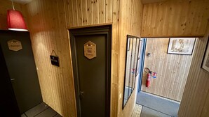 A wooden interior hallway with a door labeled "Local à Skis Poussettes," a fire extinguisher, and a small sign reading "Bureau." - Quiet corner near the mountain road (Mont-Dore)