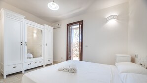 Ein Schlafzimmer mit Bett, Kleiderschrank, Badezimmer und einer Tür, die nach draußen führt.