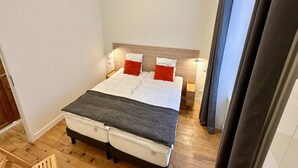Un lit bien fait, avec une tête de lit, une table de chevet et une petite table à poser près du lit.