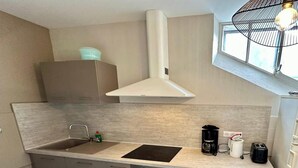 Una cocina moderna con horno empotrado, un lavamanos y una cafetera.