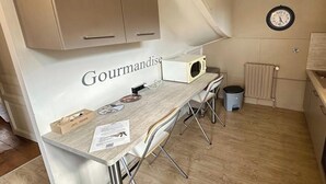 Una kitchenette con una encimera, armarios, microondas y un reloj en la pared.
