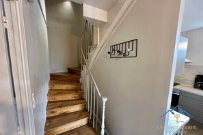 Eine Treppe mit Holzbodenstufen und weißen Geländern, die zu einer Zwischenebene mit einem an der Wand befestigten Kleiderhaken führt.