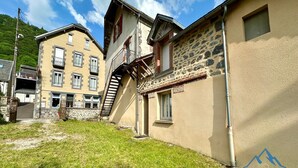 Un edificio de varios pisos con fachada de piedra, una escalera visible y un pequeño balcón.