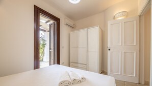 A bedroom with a bed, a wardrobe, and a door. - Room 'Villa Sterlizia - Lantana' with Shared Pool, Wi-Fi and Air Conditioning (Alliste)