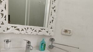A bathroom with a white sink, a mirror with a decorative frame, a soap dispenser, a towel rack, and a toilet paper holder. - Room 'Villa Sterlizia - Lantana' with Shared Pool, Wi-Fi and Air Conditioning (Alliste)