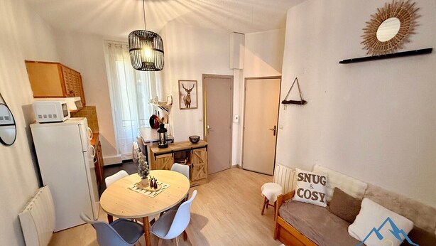 Ett kompakt bostadsutrymme med en matplats, ett litet kök och en sittgrupp.
