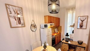 Ett kompakt kök med kylskåp, mikrovågsugn och träskåp.