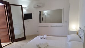 Hotellihuone, jossa on sänky, suuri peili, taulutelevisio ja vaatekaappi.