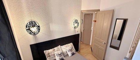 Una camera da letto con un letto, due applique, uno specchio e una porta.