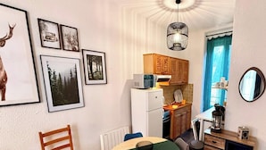 Eine kleine Küche mit Kühlschrank, Mikrowelle und Holzschränken.