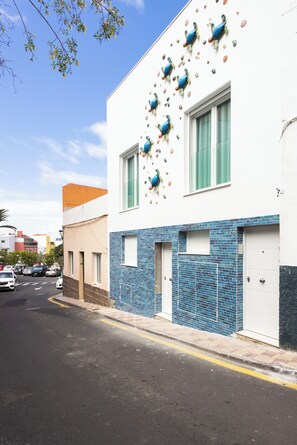 Ein Gebäude mit weißer Fassade, einem unteren Abschnitt aus blauen Fliesen und dekorativen Pfauenfiguren.
