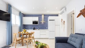 Eine moderne Küche mit weißen Schränken, einer blauen Fliesenküchenwand und einer zentralen Kochinsel mit Stühlen und einer Pflanze.