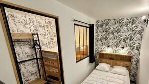 Una camera da letto con un letto a castello, un letto singolo, una testiera in legno e una parete decorata con un motivo a foglie.