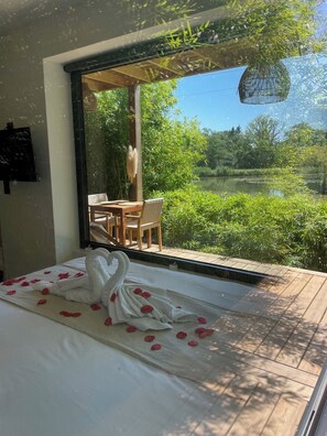 A bedroom with a bed, a window, and a view of a garden.