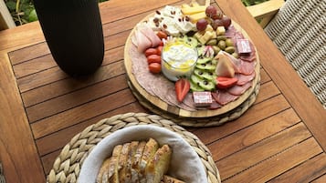 Et træbord med en charcuteribræt og en skål med skiveskåret brød.