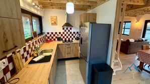 Een keuken met houten kastjes, een roestvrijstalen koelkast en een zwart-wit betegelde achterwand.