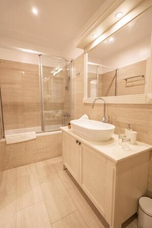 Une salle de bain moderne avec une douche à parois de verre, un lavabo sur pied et un grand miroir au-dessus du meuble-lavabo.