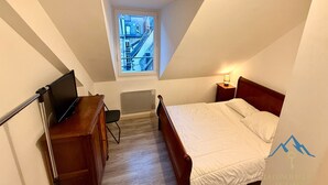 Ett sovrum med en säng, ett skrivbord, en stol, ett fönster och ett sängbord med en lampa.