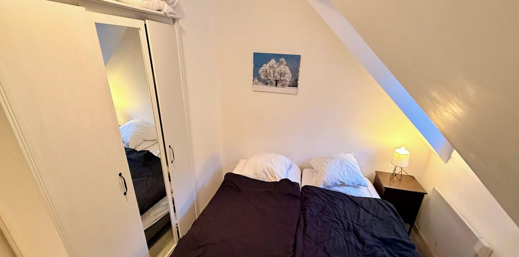 Una camera da letto con un letto, un comodino, una lampada e un quadro appeso al muro.