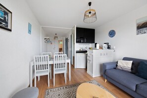 Un espacio habitable compacto con comedor, kitchenette y zona de estar.