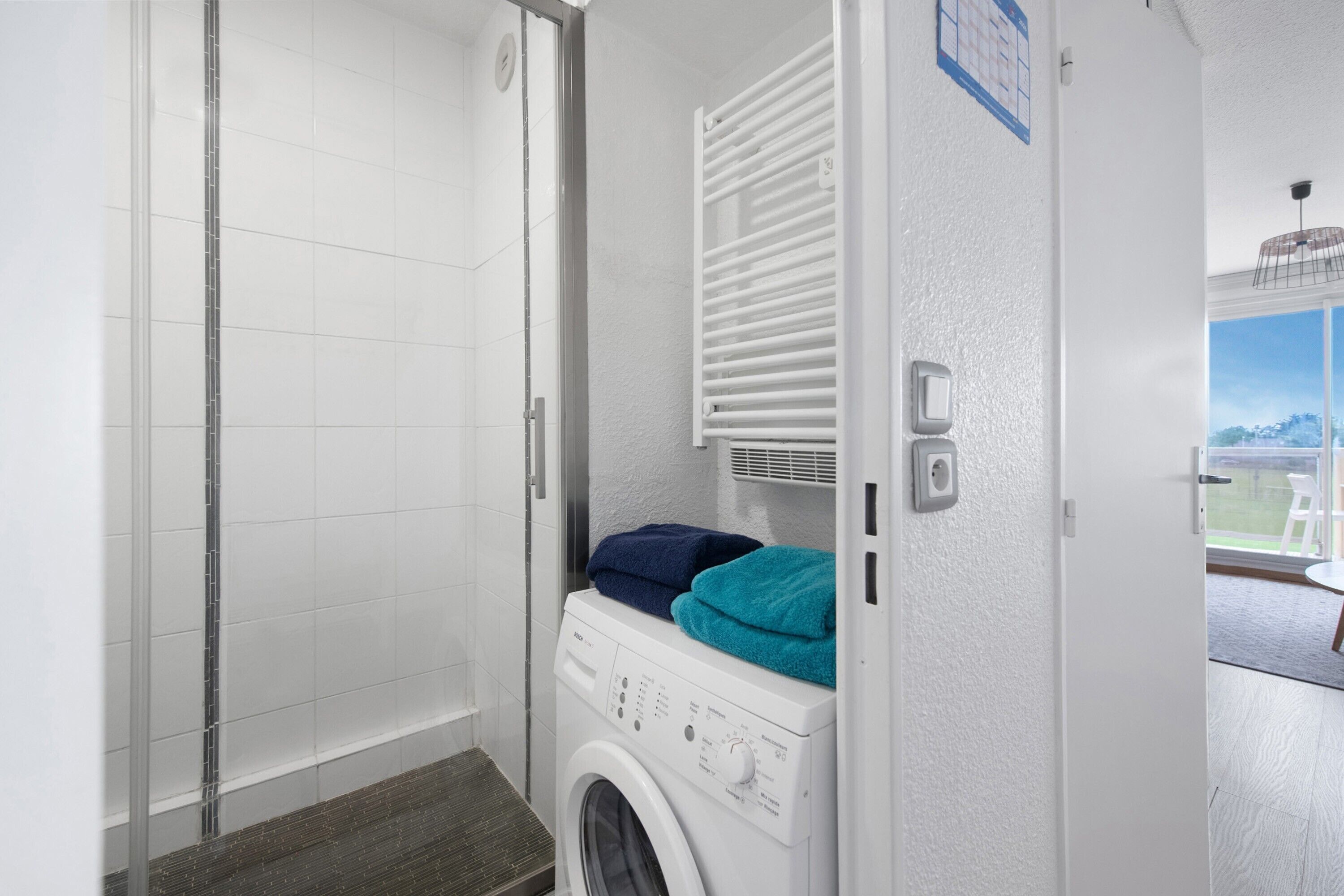 Une buanderie équipée d’un lave-linge, d’un étendoir et d’une porte donnant sur un balcon avec vue.