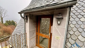 Entrada de um edifício com porta de madeira, número 28, e fachada de pedra.