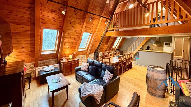 Um quarto acolhedor no estilo loft, com decoração em madeira, um sofá de couro preto, uma mesa de jantar e uma cozinha.