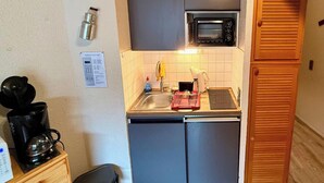 Eine kleine Küche mit integriertem Mikrowellenherd, Spüle und Kaffeemaschine.