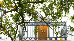 Une entrée d’immeuble avec un balcon, un paillasson et une porte dotée d’un panneau en verre.