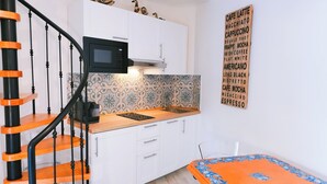 Une cuisine avec des meubles blancs, un four à micro-ondes et un panneau décoratif sur le mur sur le thème du café.