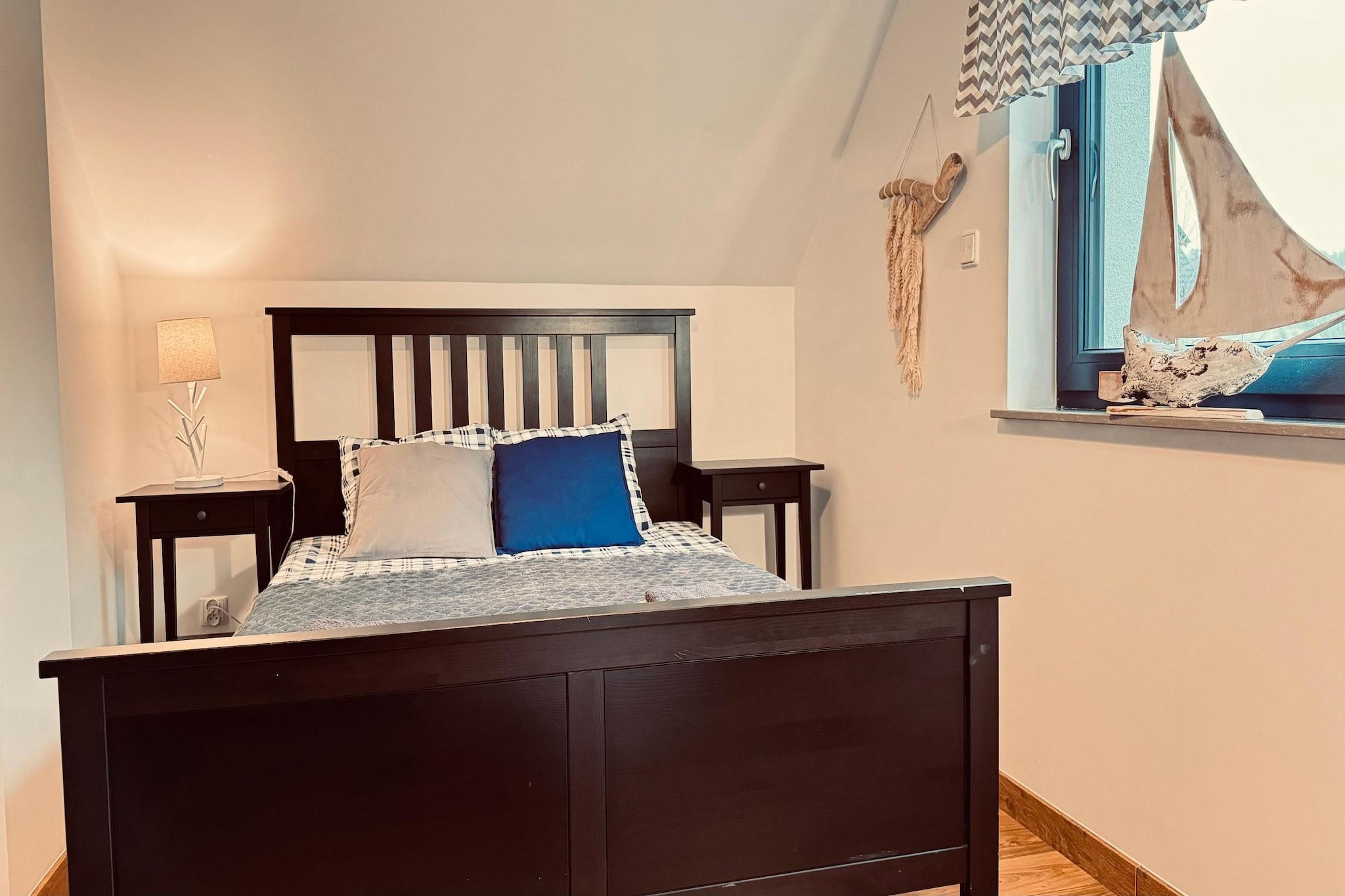 Une chambre à coucher avec un lit, des tables de chevet, une lampe et une fenêtre avec des rideaux.