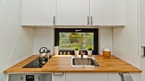 A compact kitchen with a wooden countertop, stainless steel sink, and white cabinets. - Holiday home, sea, jacuzzi, for 3 people (Rozewie)