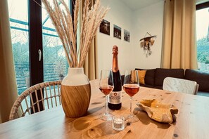 Ein Holztisch mit einer Flasche Duchessina Fragolino Wein, zwei Gläsern, einer Vase mit getrockneten Pflanzen und einem rustikalen Brotkorb.