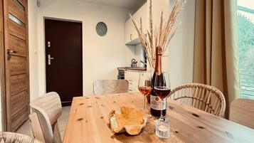 Une table de salle à manger en bois, avec une bouteille de vin, un verre et un bol décoratif.