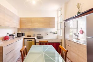 A modern kitchen with wooden cabinets, a glass dining table, and a window with a view.