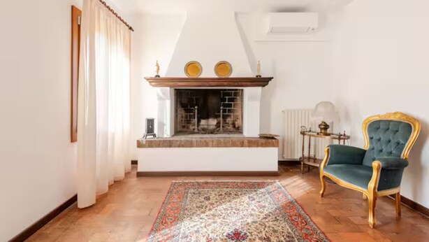 A living room with a fireplace, a blue armchair, and a patterned rug. - Venetian Elegance Villa - near Venice historic center (Mira)