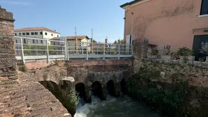 A stone bridge over a flowing river, with a building on the right and another in the background. - Venetian Elegance Villa - near Venice historic center (Mira)