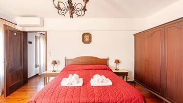 A bedroom with a wooden bed, two bedside tables, a chandelier, and a wardrobe.