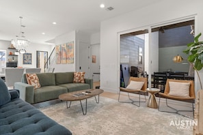 Ein modernes Wohnzimmer mit einer Couch, einem Couchtisch und Sesseln. Eine Treppe führt zu einer weiteren Ebene.