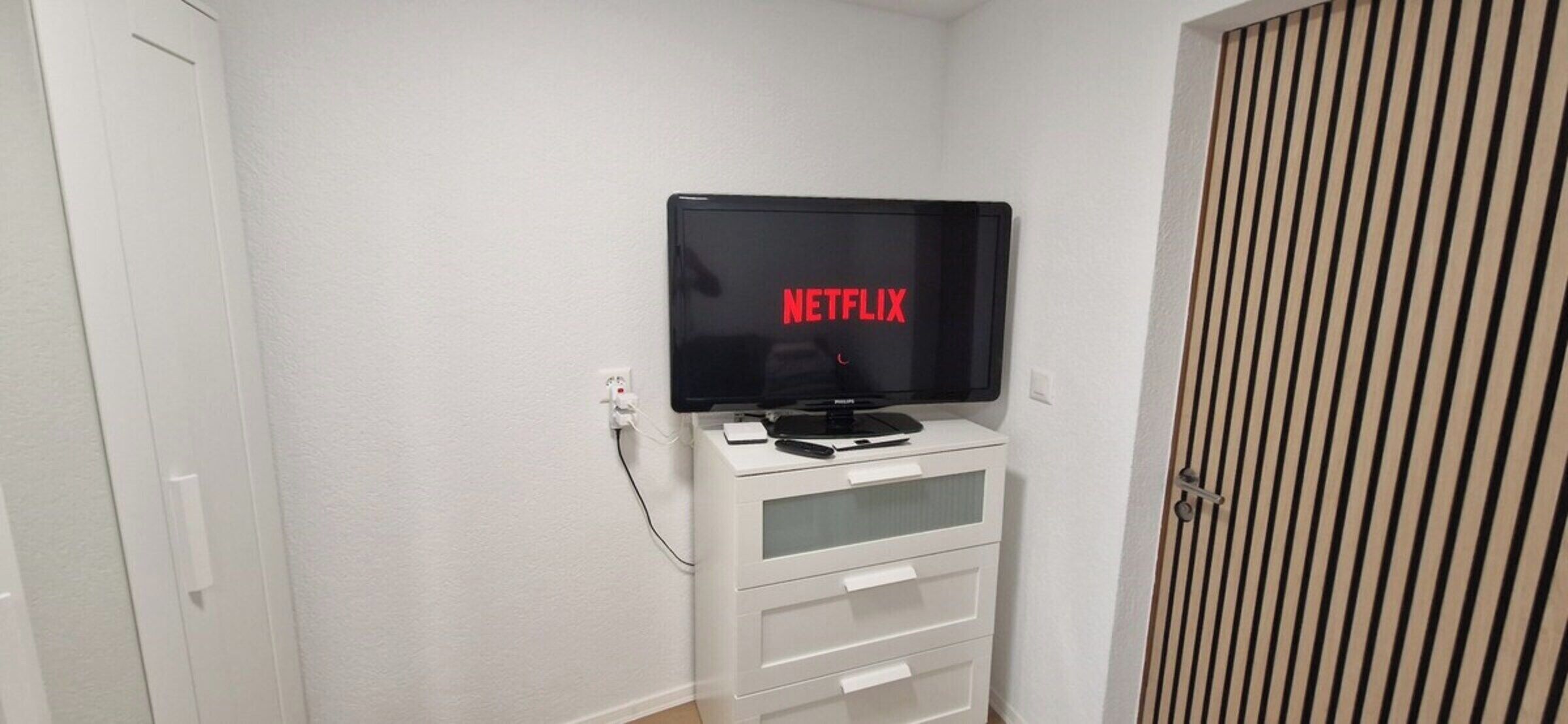 Un mueble blanco de entretenimiento con un televisor de pantalla plana mostrando el logotipo de Netflix.