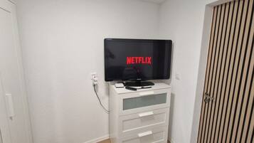 Un mueble blanco de entretenimiento con un televisor de pantalla plana mostrando el logotipo de Netflix.