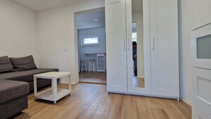 Una sala de estar moderna con un sofá gris, una mesita auxiliar blanca y un armario blanco.