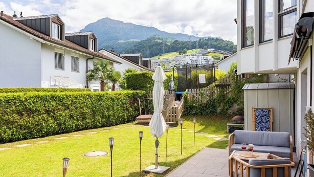 Una propiedad residencial con un patio, mobiliario exterior y vistas a un pueblo y montañas.